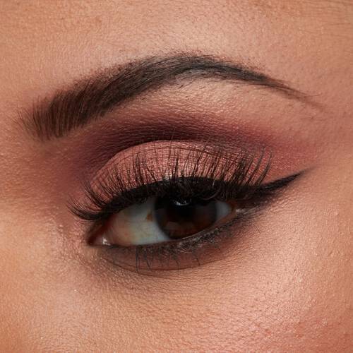 Nahaufnahme eines Auges mit bronzefarbenem Lidschatten, schwarzem Eyeliner und langen, geschwungenen Wimpern
