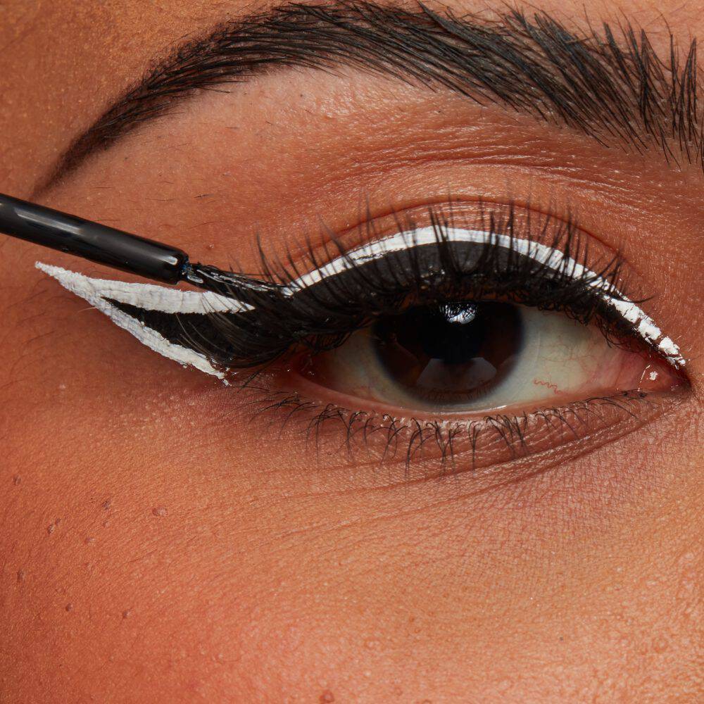 Frau zieht sich mit flussigen Eyeliner einen Lidstrich