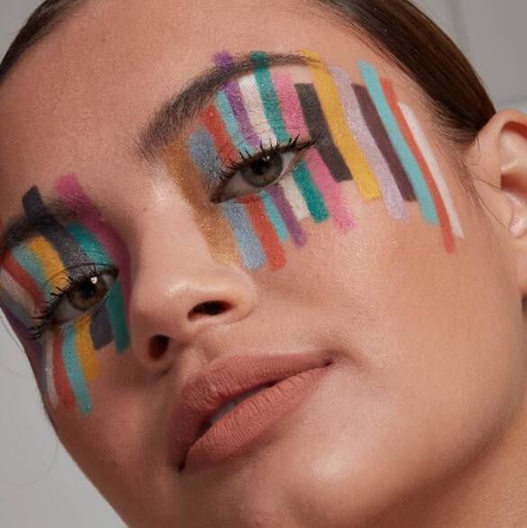 Nahaufnahme einer jungen Frau, deren Augen bunt mit verschieden-farbigen Streifen der Epic Wear Liner Sticks von NYX Professional Makeup geschminkt sind.