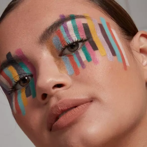 Nahaufnahme einer jungen Frau, deren Augen bunt mit verschieden-farbigen Streifen der Epic Wear Liner Sticks von NYX Professional Makeup geschminkt sind.