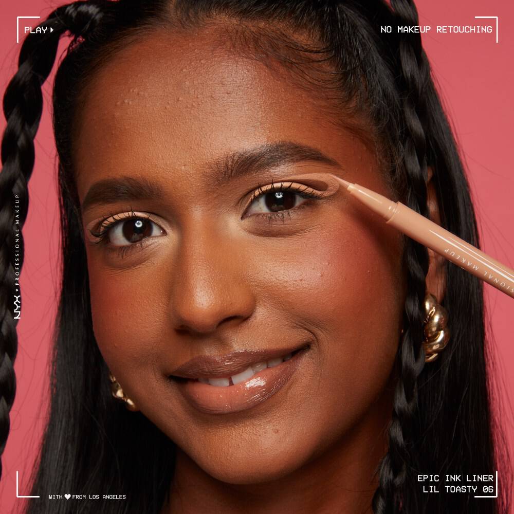 Gesicht einer lachelnden Frau mit dunklen Haaren, die mit dem Epic Wear Eyeliner einen geschwungen Eyeliner zieht