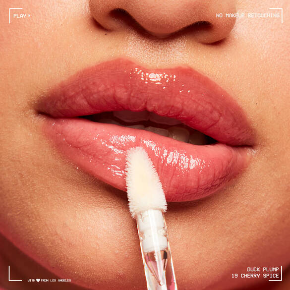 Nahaufnahme von Lippen mit glanzendem Lipgloss, der mit einem Applikator aufgetragen wird. Marke: Duck Plump, Farbe: Cherry Spice.