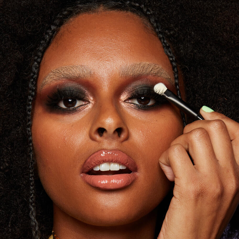 Frau mit dunklem Hautton schminkt sich dunkle Smokey Eyes