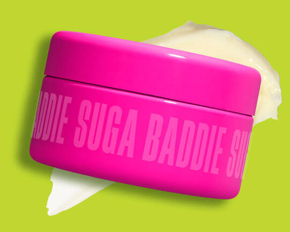 Ein Tiegel der NYX Body Butter „Suga Baddie“ prasentiert seine cremeweiße Textur vor einem kontrastreichen grunen Hintergrund.