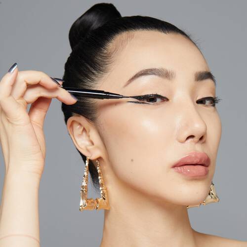 Frau zieht sich mit Filz Eyeliner den Lidstrich