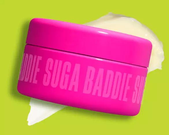 Ein Tiegel der NYX Suga Baddie Fat Oil Body Butter mit einer cremeweißen Texturprobe auf grunem Grund.