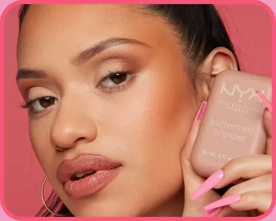 Model prasentiert den warmen, sonnengekussten Glow des aufgetragenen NYX Buttermelt Bronzers auf den Wangenknochen mit dem Produkt in der Hand.