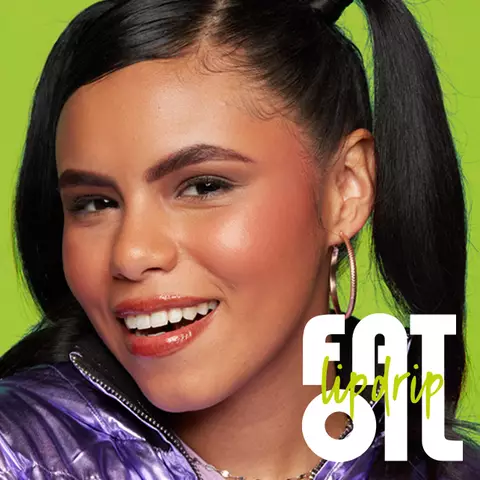Nahaufnahme einer lachelnden, jungen Frau mit Lipgloss auf den Lippen und die Aufschrift "Fat Oil Lip Drip"