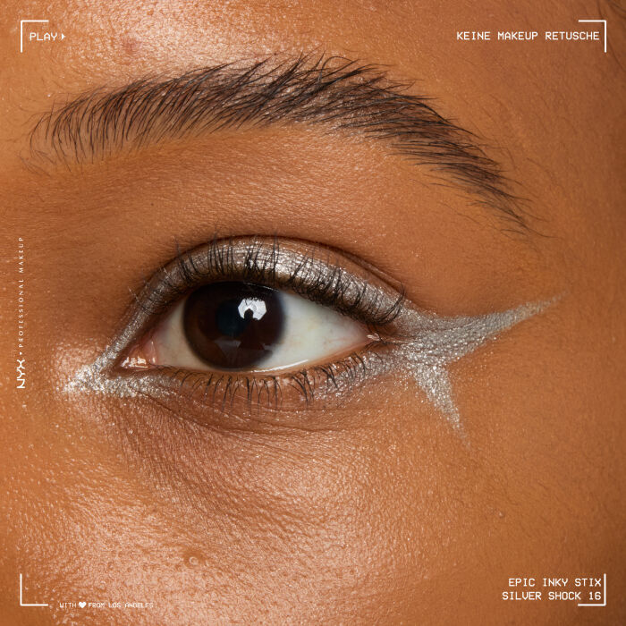 Nahaufnahme eines Auges mit einem aufwendigen Eyeliner-Design. Der Eyeliner beginnt am oberen Wimpernkranz, zieht sich uber das Lid und formt mehrere geschwungene, tribalahnliche Linien, die sich bis zur Augenbraue erstrecken und ein markantes, grafisches Muster bilden.