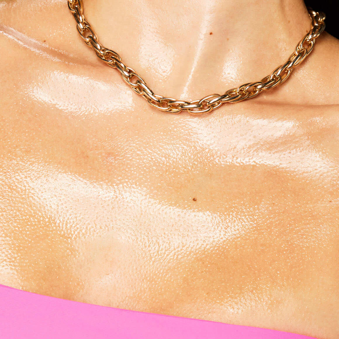 Ein eingeöltes Dekolleté mit Goldschmuck zeigt den intensiven Glanzeffekt des Fat Oil Body Oils.